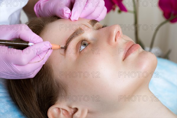 Permanent microblasting tattooing freckles to a woman in a beauty salon