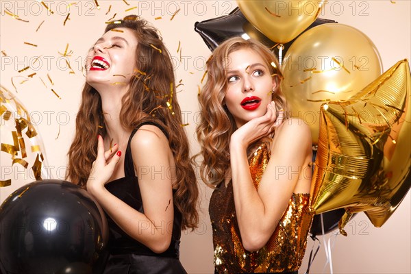 Beautiful young women in elegant evening dresses with festive balloons. Beauty face. Photo taken in the studio