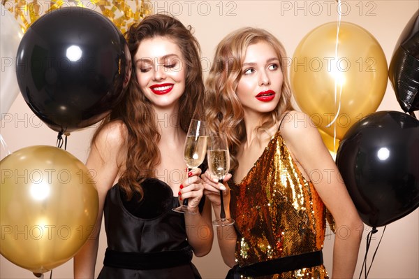 Beautiful young women in elegant evening dresses with festive balloons. Beauty face. Photo taken in the studio