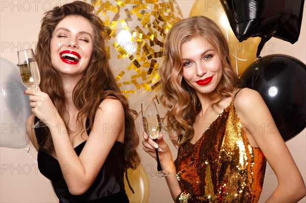 Beautiful young women in elegant evening dresses with festive balloons. Beauty face. Photo taken in the studio