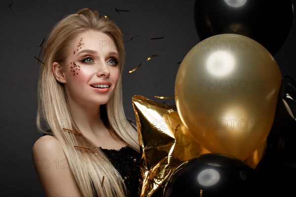 Beautiful young girl in elegant evening dress with festive balloons. Beauty face. Photo taken in the studio