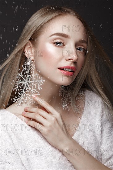 Beautiful blonde girl in a winter image with snow. Beauty face. Photo taken in the studio