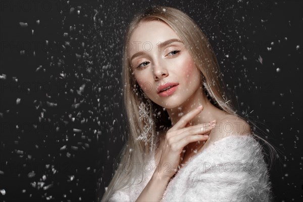 Beautiful blonde girl in a winter image with snow. Beauty face. Photo taken in the studio