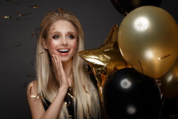 Beautiful young girl in elegant evening dress with festive balloons. Beauty face. Photo taken in the studio