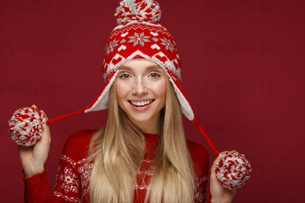 Beautiful blonde girl in a New Year's image in warm hat and sweater. Beauty face with festive makeup. Photo taken in the studio