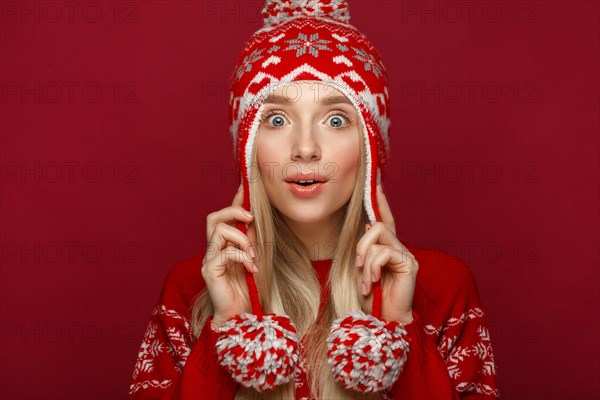Beautiful blonde girl in a New Year's image in warm hat and sweater. Beauty face with festive makeup. Photo taken in the studio