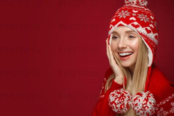 Beautiful blonde girl in a New Year's image in warm hat and sweater. Beauty face with festive makeup. Photo taken in the studio