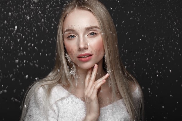Beautiful blonde girl in a winter image with snow. Beauty face. Photo taken in the studio