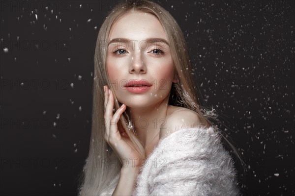 Beautiful blonde girl in a winter image with snow. Beauty face. Photo taken in the studio