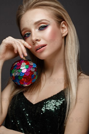 Beautiful young girl in elegant evening dress with festive christmas ball. Beauty face. Photo taken in the studio