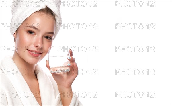 Beautiful tender young girl in a white towel with clean fresh skin posing in front of the camera. Beauty face. Skin care. Photo taken in studio on a white isolate background