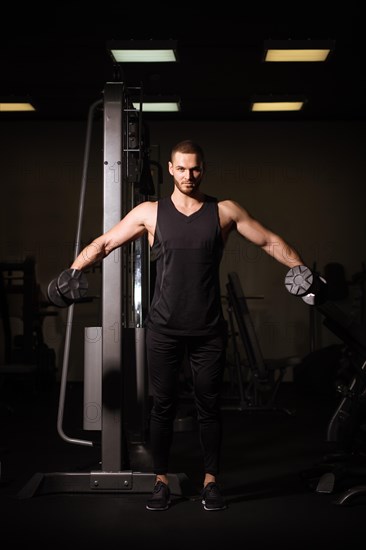 Sporty sexy men with great abdominal muscles in black sportswear working out in the gym