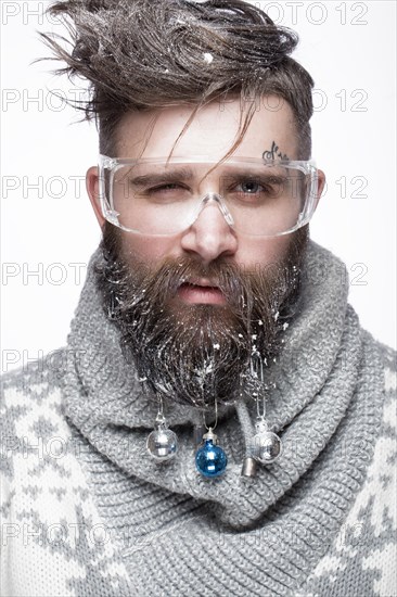 Funny bearded man in a New Year's image with snow and decorations on his beard. Feast of Christmas. Photos shot in the studio