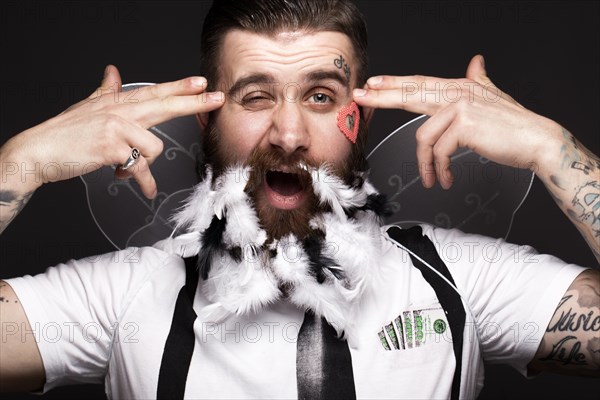 Funny bearded man with feathers and wings in the image of Cupid Valentine's Day. Portrait shot in studio