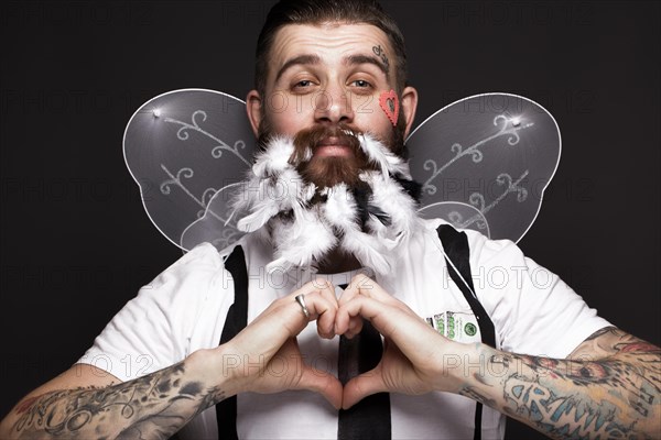 Funny bearded man with feathers and wings in the image of Cupid Valentine's Day. Portrait shot in studio