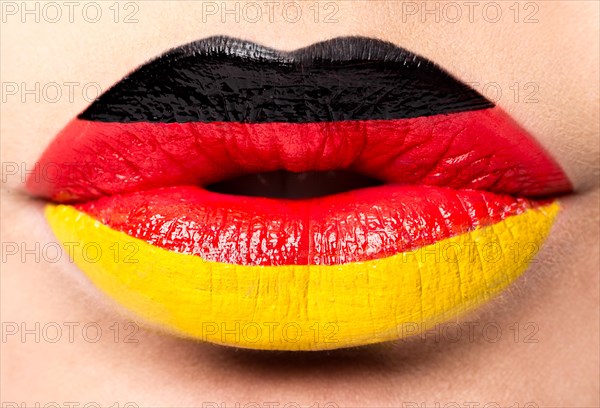 Female lips close up with a picture of the flag of Germany. black