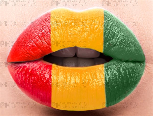 Female lips close up with a picture of the flag of Guinea. Yellow