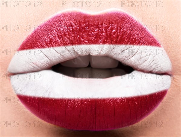 Female lips close up with a picture of the flag of Latvia. white