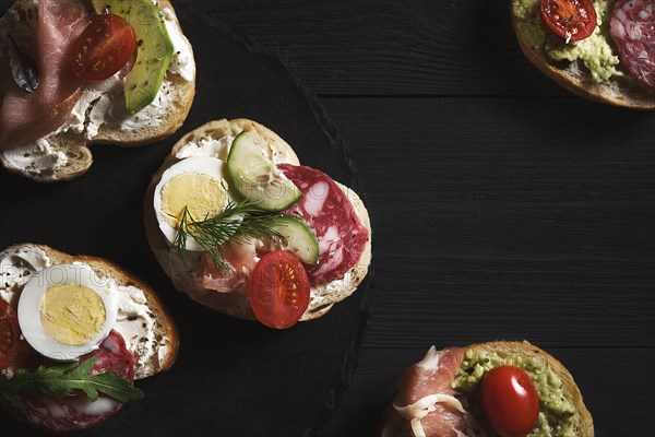 Sandwiches with curd cheese and vegetables and sausage on wooden background