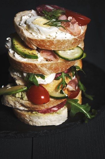 Sandwiches with curd cheese and vegetables and sausage on wooden background