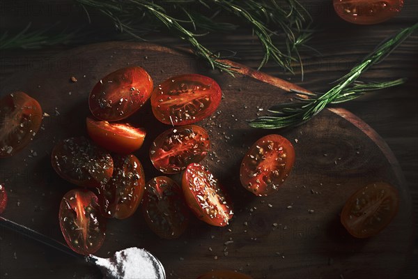 Cherry tomatoes on a wooden board with seasoning and herbs