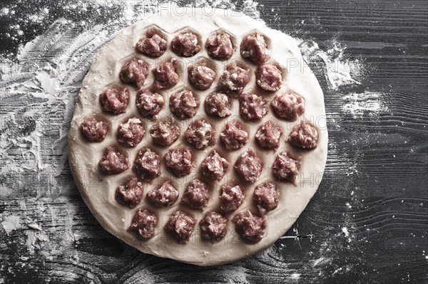 Handmade homemade dumplings on a metal tray on a wooden background with flour. Diy meat dumplings