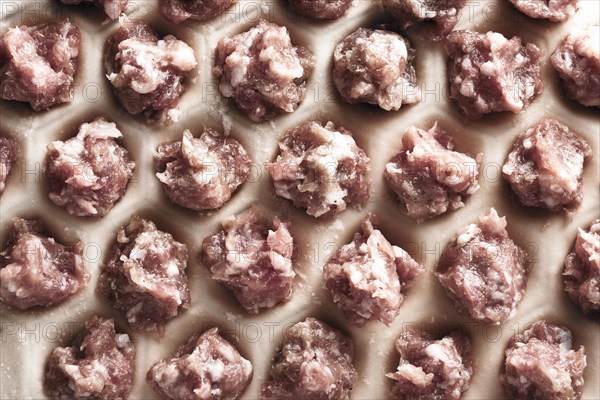 Handmade homemade dumplings on a metal tray on a wooden background with flour. Diy meat dumplings