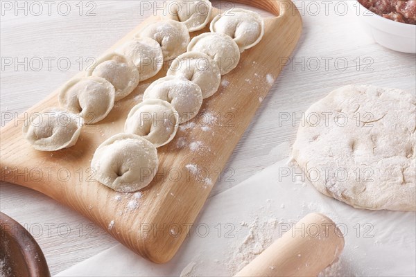 Handmade homemade dumplings on a wooden tray on a white plate with flour. Diy meat dumplings