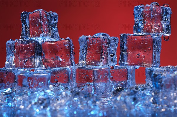 Transparent cold ice cubes on a red background