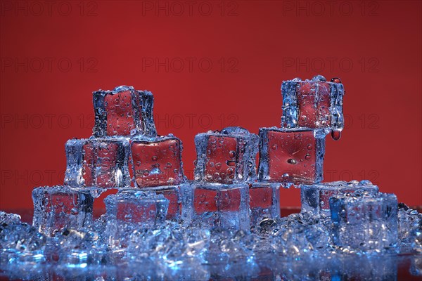 Transparent cold ice cubes on a red background