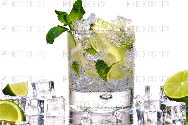 Glass of Mojito summer alcoholic cocktail with ice cubes mint and lime on white background with raw lime and mint leaf