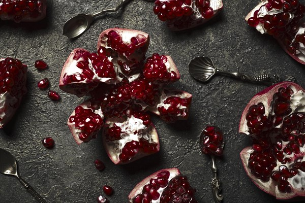 Metal background with pomegranate berries and retro spoons. Vintage style photo