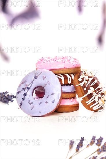 Sweet multicolored donuts on a white background with lavender flowers