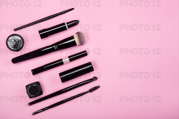 Set of brushes and cosmetic products on a pink background