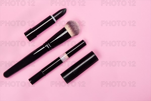 Set of brushes and cosmetic products on a pink background