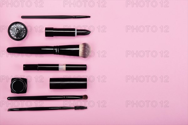 Set of brushes and cosmetic products on a pink background