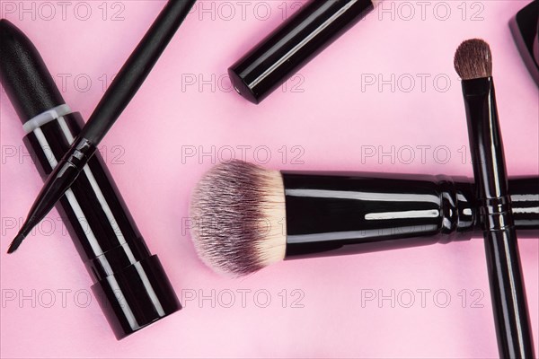 Set of brushes and cosmetic products on a pink background