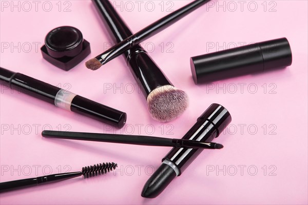 Set of brushes and cosmetic products on a pink background