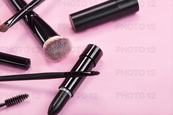 Set of brushes and cosmetic products on a pink background