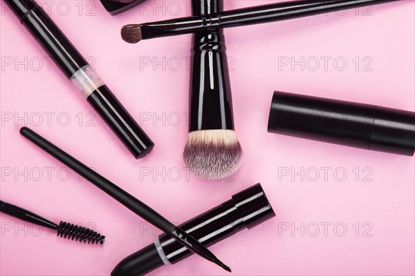 Set of brushes and cosmetic products on a pink background