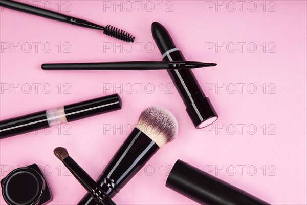 Set of brushes and cosmetic products on a pink background