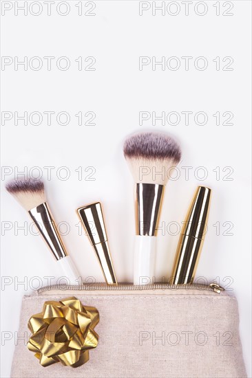 Set of brushes and cosmetic products in a cosmetic bag on a white background