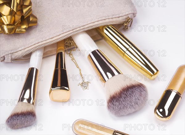 Set of brushes and cosmetic products in a cosmetic bag on a white background