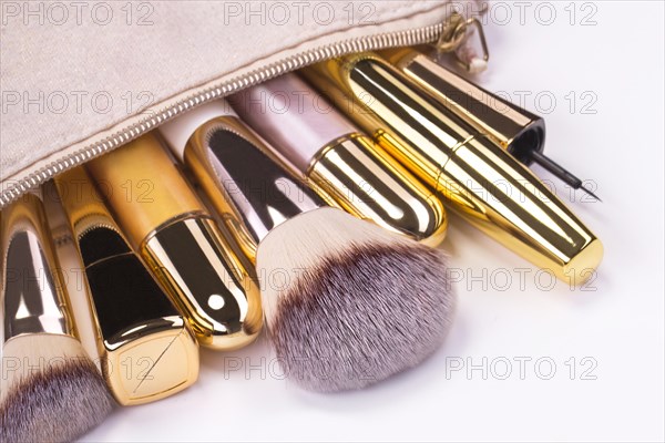 Set of brushes and cosmetic products in a cosmetic bag on a white background