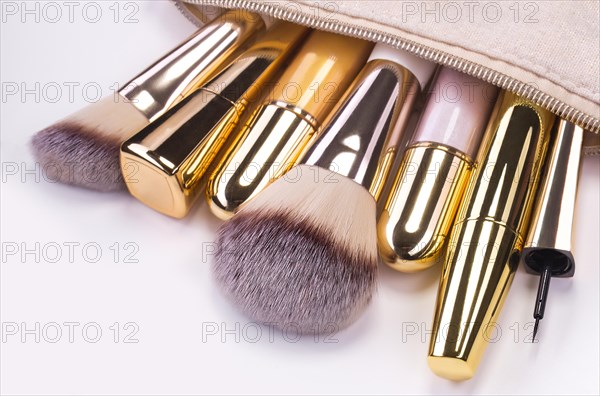 Set of brushes and cosmetic products in a cosmetic bag on a white background