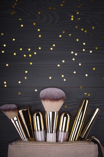 Set of brushes and cosmetic products in a cosmetic bag on a grey background