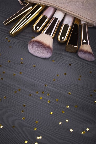 Set of brushes and cosmetic products in a cosmetic bag on a grey background