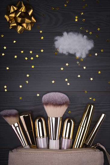 Set of brushes and cosmetic products in a cosmetic bag on a grey background