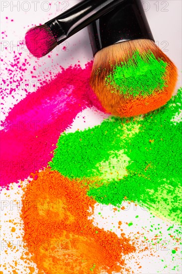 Cheek brush with neon cosmetic powder colorful pile and isolated on white background
