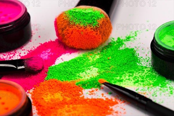 Cheek brush with neon cosmetic powder colorful pile and isolated on white background